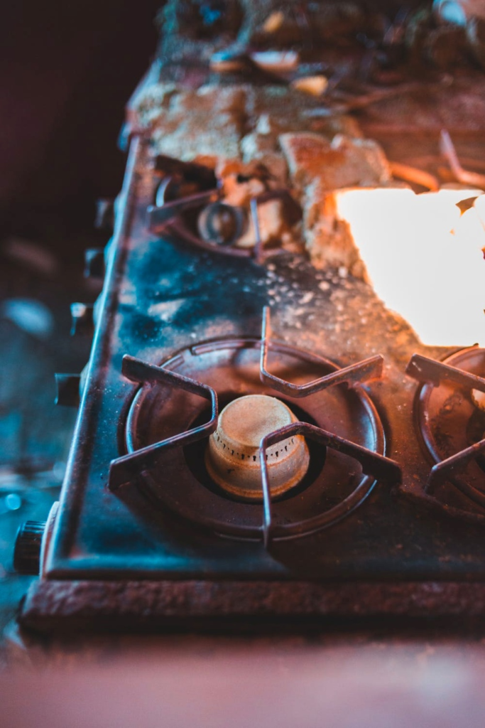 A zoomed-in photo of a dirty, crusty gas stove top.