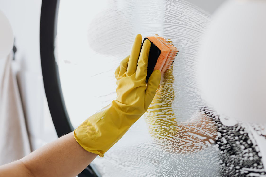 A residential cleaner cleaning a mirror