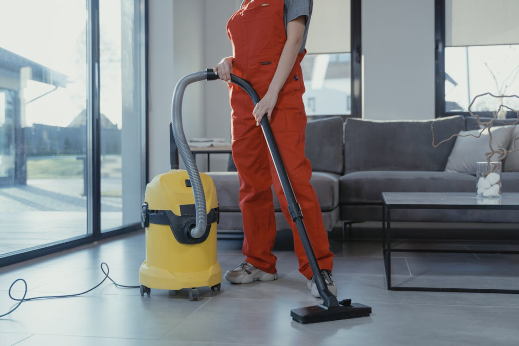 A person in orange overalls vacuuming during house cleaning